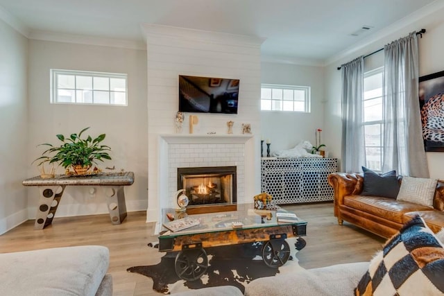 living room featuring baseboards, a brick fireplace, light wood-style flooring, and crown molding