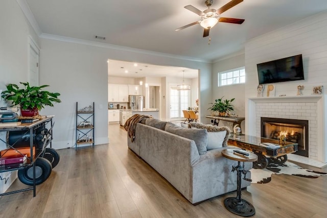 living area featuring ornamental molding, light wood-type flooring, and visible vents