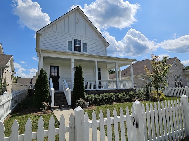 view of front of property with covered porch, a fenced front yard, and board and batten siding