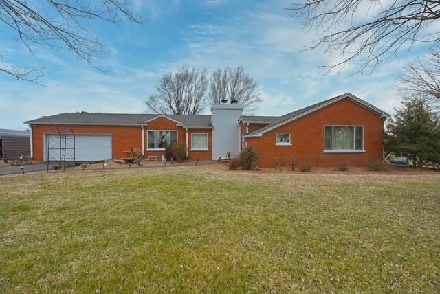 single story home featuring a front lawn, driveway, a chimney, and an attached garage