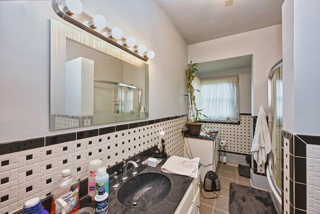 full bathroom featuring tile walls, a stall shower, wainscoting, vanity, and tile patterned flooring