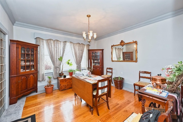 dining room with a chandelier, crown molding, and light wood-style floors