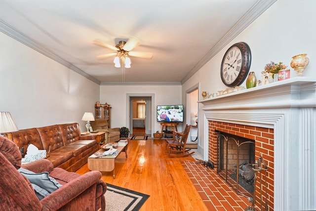 living area featuring ceiling fan, ornamental molding, a fireplace, and wood finished floors