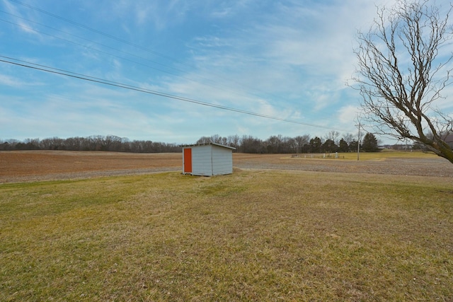 view of yard with an outbuilding, a rural view, and a storage shed