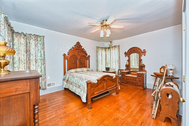 bedroom featuring light wood-type flooring, ceiling fan, visible vents, and baseboards