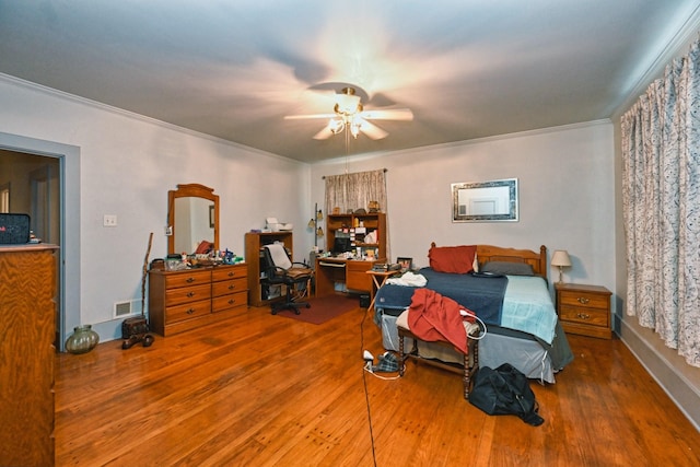 bedroom featuring ceiling fan, wood finished floors, and crown molding