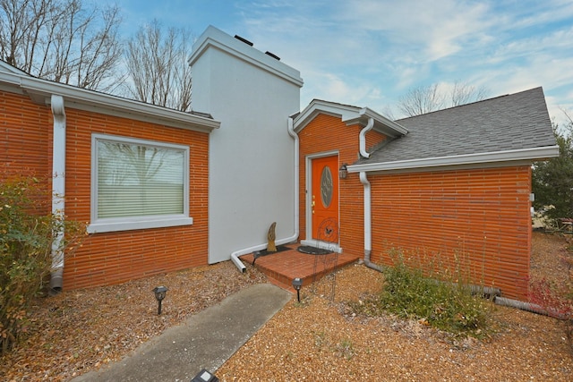 view of side of property with roof with shingles and a chimney