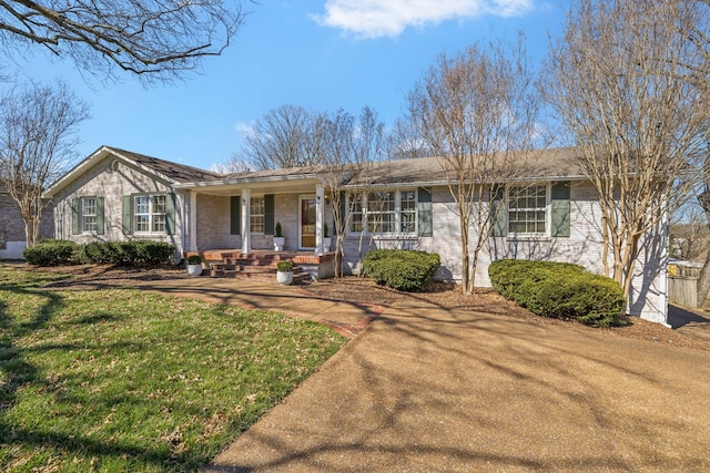 single story home with a front yard, covered porch, and brick siding