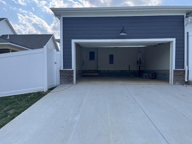 garage featuring concrete driveway and fence