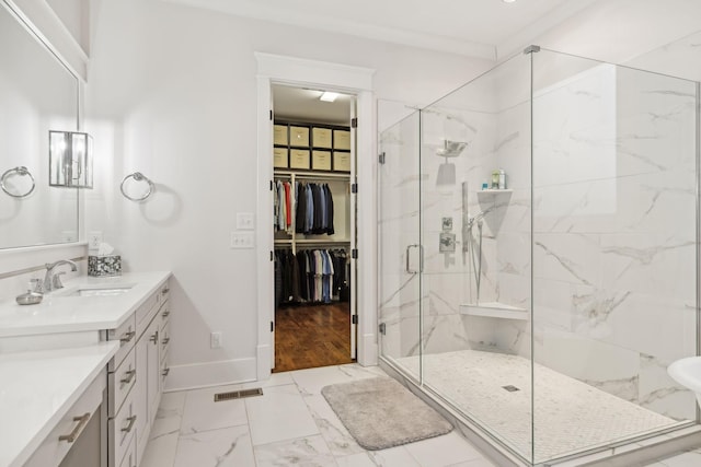 full bath featuring marble finish floor, a marble finish shower, a spacious closet, vanity, and baseboards