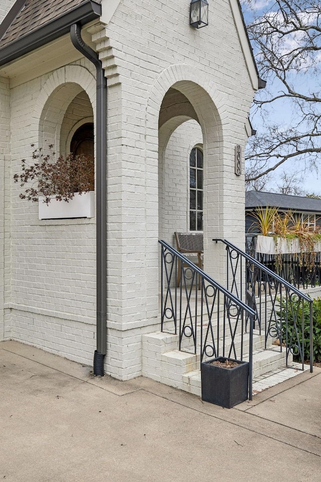 entrance to property with brick siding and roof with shingles