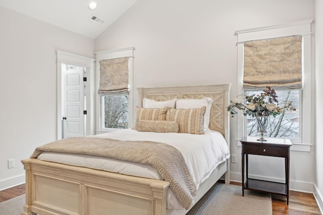 bedroom with lofted ceiling, baseboards, visible vents, and wood finished floors