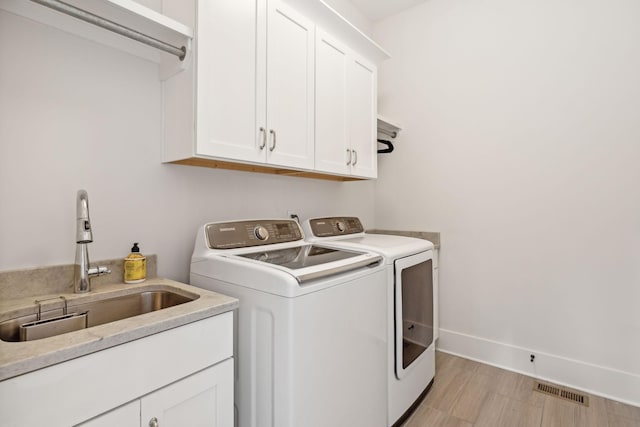 laundry room with cabinet space, baseboards, visible vents, washer and dryer, and a sink