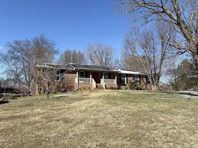 ranch-style house featuring covered porch, brick siding, and a front yard