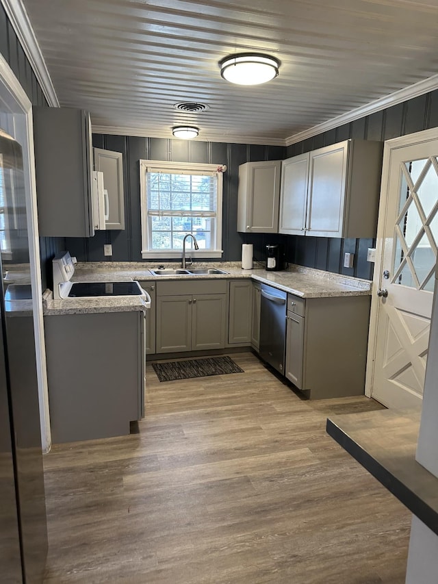 kitchen with crown molding, gray cabinetry, stainless steel dishwasher, light wood-style floors, and a sink