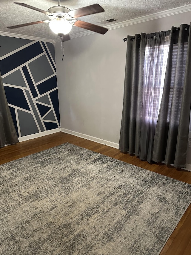 spare room with visible vents, dark wood-type flooring, a textured ceiling, and ornamental molding