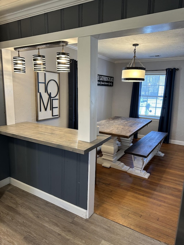 kitchen featuring hanging light fixtures, wood finished floors, and crown molding