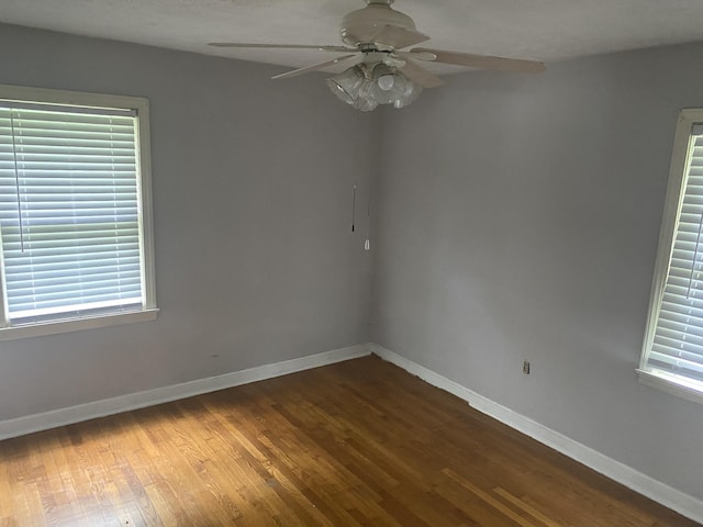 spare room with wood finished floors, a ceiling fan, and baseboards