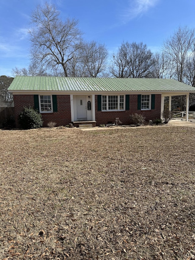 ranch-style house featuring a carport, brick siding, and metal roof