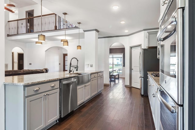 kitchen with stainless steel appliances, open floor plan, hanging light fixtures, and gray cabinets