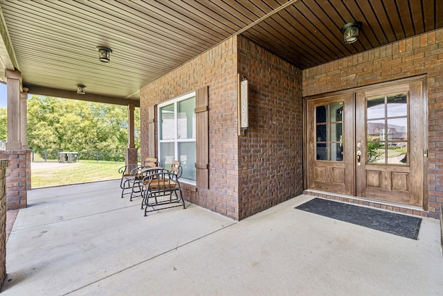 entrance to property with covered porch and brick siding