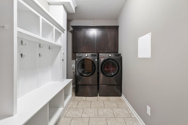 laundry room featuring cabinet space, washer and clothes dryer, baseboards, and light tile patterned floors