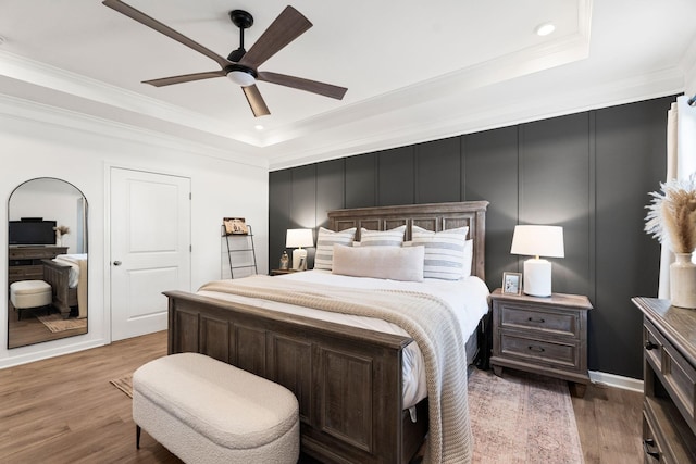 bedroom with ornamental molding, a tray ceiling, and wood finished floors