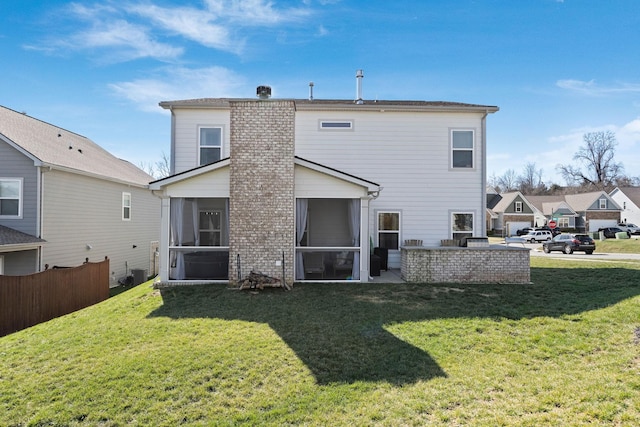 rear view of house featuring fence, a sunroom, a lawn, a residential view, and a chimney