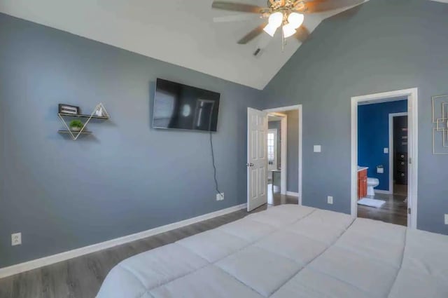 bedroom featuring lofted ceiling, ceiling fan, ensuite bath, wood finished floors, and baseboards