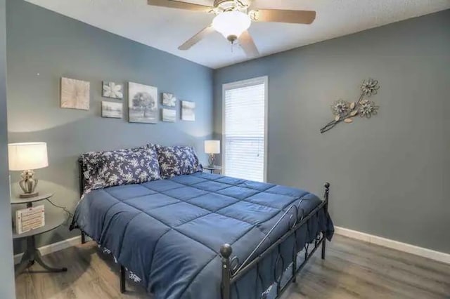 bedroom with a ceiling fan, baseboards, and wood finished floors