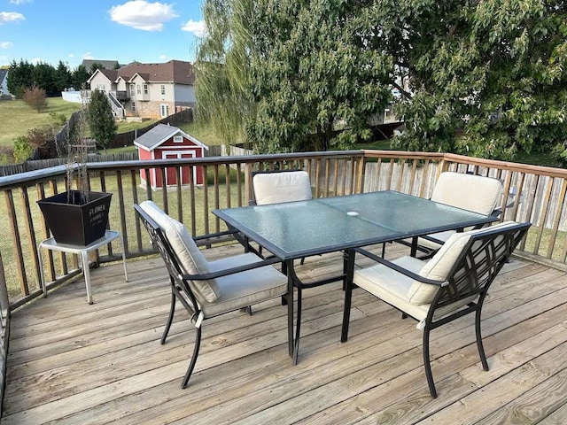 deck with a storage shed, a yard, outdoor dining area, and an outbuilding