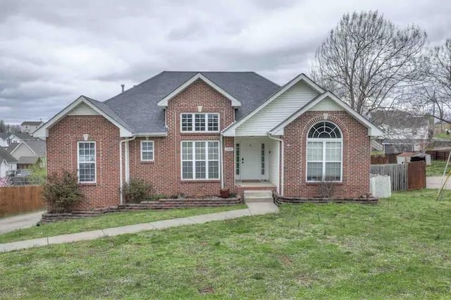 view of front of property featuring fence, a front lawn, and brick siding