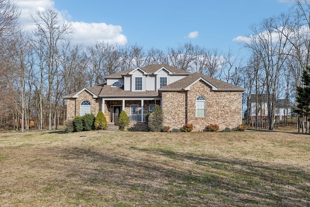 view of front of property with a porch, a front yard, brick siding, and a shingled roof