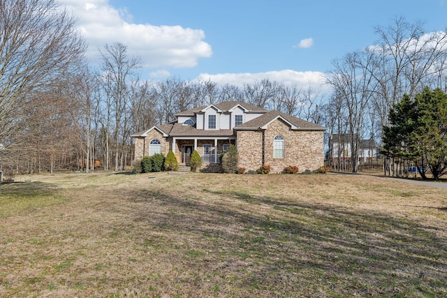 view of front of home featuring covered porch, roof with shingles, a front lawn, and brick siding