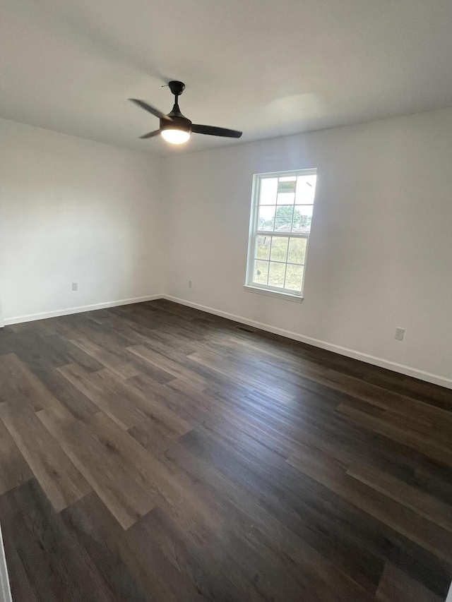 spare room featuring ceiling fan, baseboards, and dark wood-style flooring