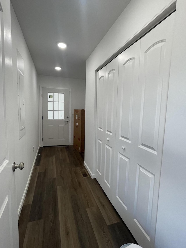 corridor with visible vents, baseboards, and dark wood-style floors