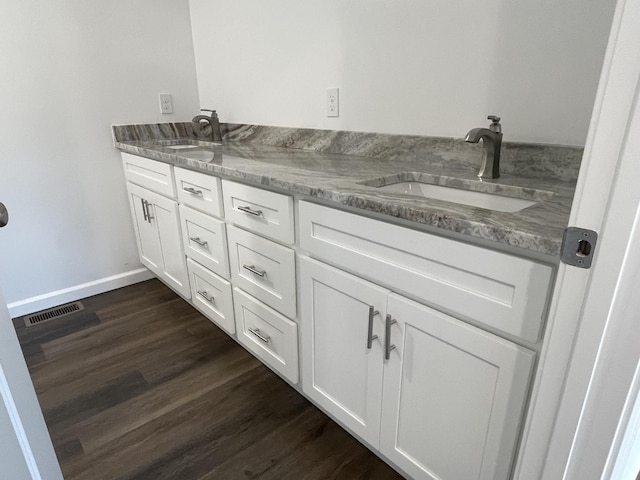 bathroom featuring double vanity, visible vents, wood finished floors, and a sink