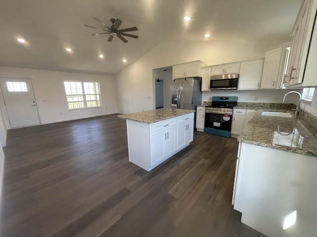 kitchen with appliances with stainless steel finishes, open floor plan, a center island, white cabinetry, and a sink