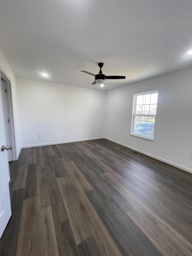 spare room featuring dark wood-style floors, baseboards, visible vents, and a ceiling fan