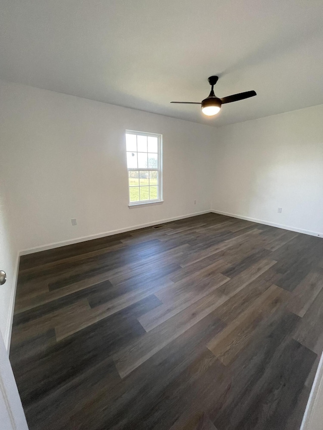 spare room with a ceiling fan, baseboards, and dark wood-type flooring