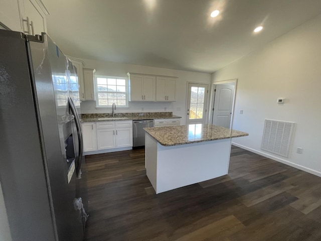 kitchen with stainless steel appliances, a sink, visible vents, white cabinets, and a center island