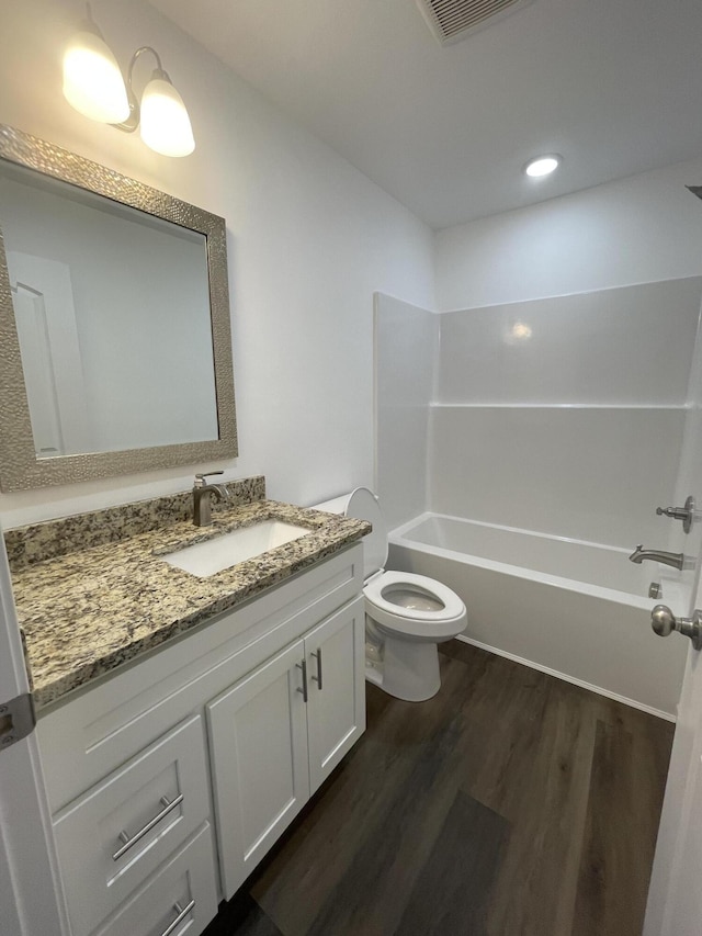 bathroom featuring visible vents, shower / bathing tub combination, toilet, vanity, and wood finished floors