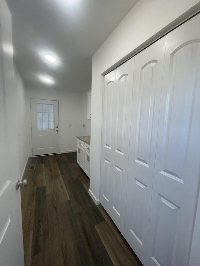 hallway featuring dark wood-style floors and baseboards