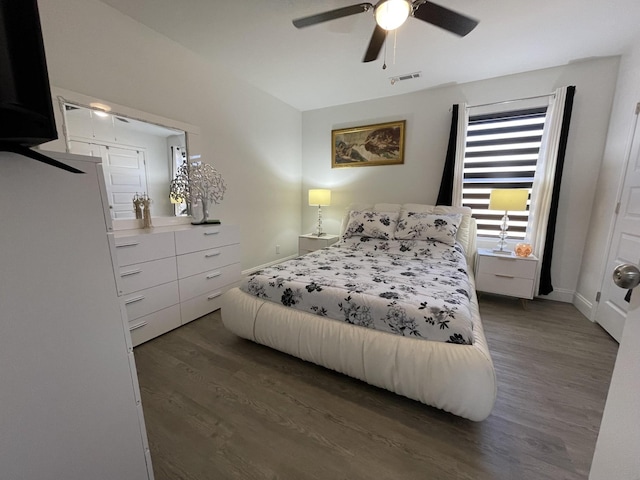 bedroom with dark wood-style floors, visible vents, ceiling fan, and baseboards