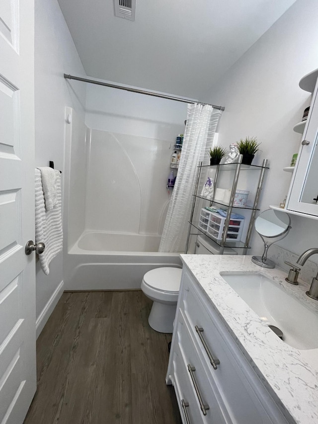 bathroom featuring visible vents, toilet, wood finished floors, shower / tub combo with curtain, and vanity