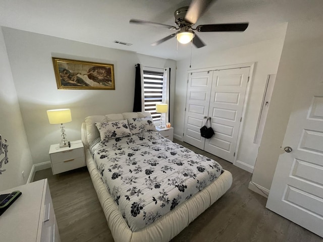 bedroom with ceiling fan, dark wood-style flooring, visible vents, baseboards, and a closet