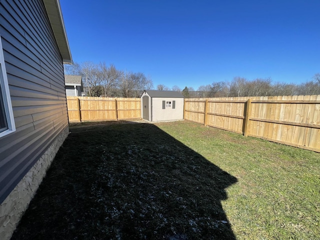 view of yard with a fenced backyard, a storage unit, and an outbuilding