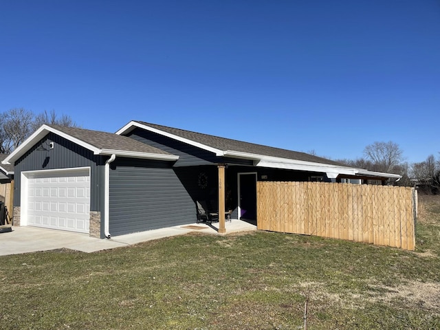 view of front of house featuring a garage, fence, concrete driveway, roof with shingles, and a front yard