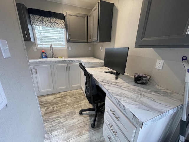 office featuring a sink, light wood-style flooring, and built in desk