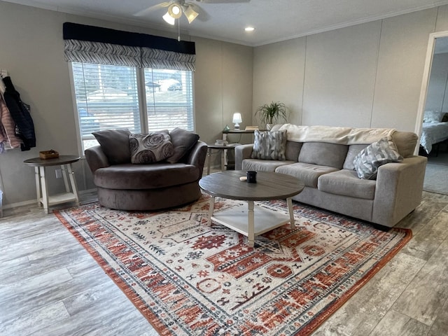 living area with ornamental molding, a ceiling fan, and wood finished floors